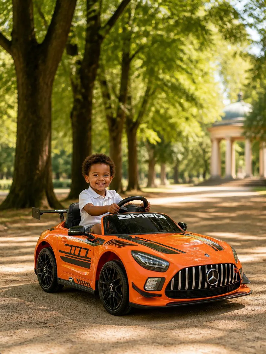 Jeune enfant souriant au volant d'une Mercedes GT3 AMG électrique orange, dans une allée de parc bordée d'arbres