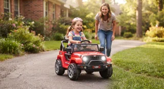 Sécurité voiture électrique enfant : petite fille casquée au volant d'une Jeep 12V rouge surveillée par sa mère lors des premières sorties