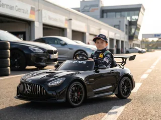 Mercedes-AMG GT3 12V noir, enfant en combinaison de pilote installé au volant, sur un circuit automobile