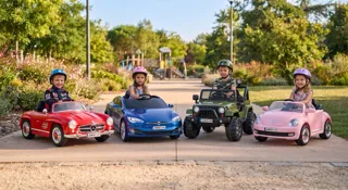 Quatre enfants au volant de voitures électriques (Mercedes 300 SL rouge, berline bleue, Jeep 4x4 verte, Coccinelle rose) dans un parc, comparatif pour choisir la voiture électrique enfant idéale