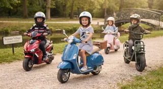 Quatre enfants à scooter électrique dans un parc, dont une Vespa bleue et une Vespa rose, guide du scooter électrique enfant