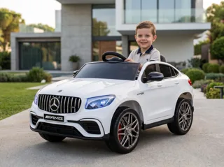 Mercedes GLC 63 AMG 12V blanc, enfant souriant au volant devant une villa contemporaine