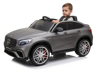Mercedes GLC 63 AMG 12V gris mat, enfant installé au volant, trois-quarts avant, fond blanc studio