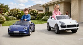 Taycan bleue et Cayenne blanche électriques pour enfant dans une allée, deux enfants au volant, illustration du guide Quelle Porsche électrique pour enfant Taycan ou Cayenne