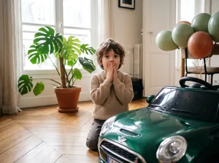 Enfant de 5 ans découvrant sa voiture électrique le matin de son anniversaire