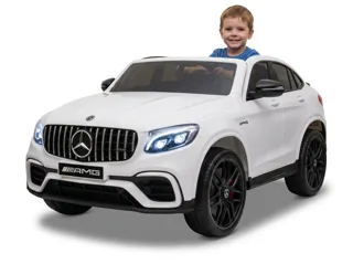 Mercedes GLC 63 AMG 12V blanc, enfant souriant au volant, trois-quarts avant, fond blanc studio