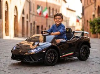 Voiture de course électrique enfant Lamborghini Huracán 12V noire, garçon au volant dans une rue pavée italienne